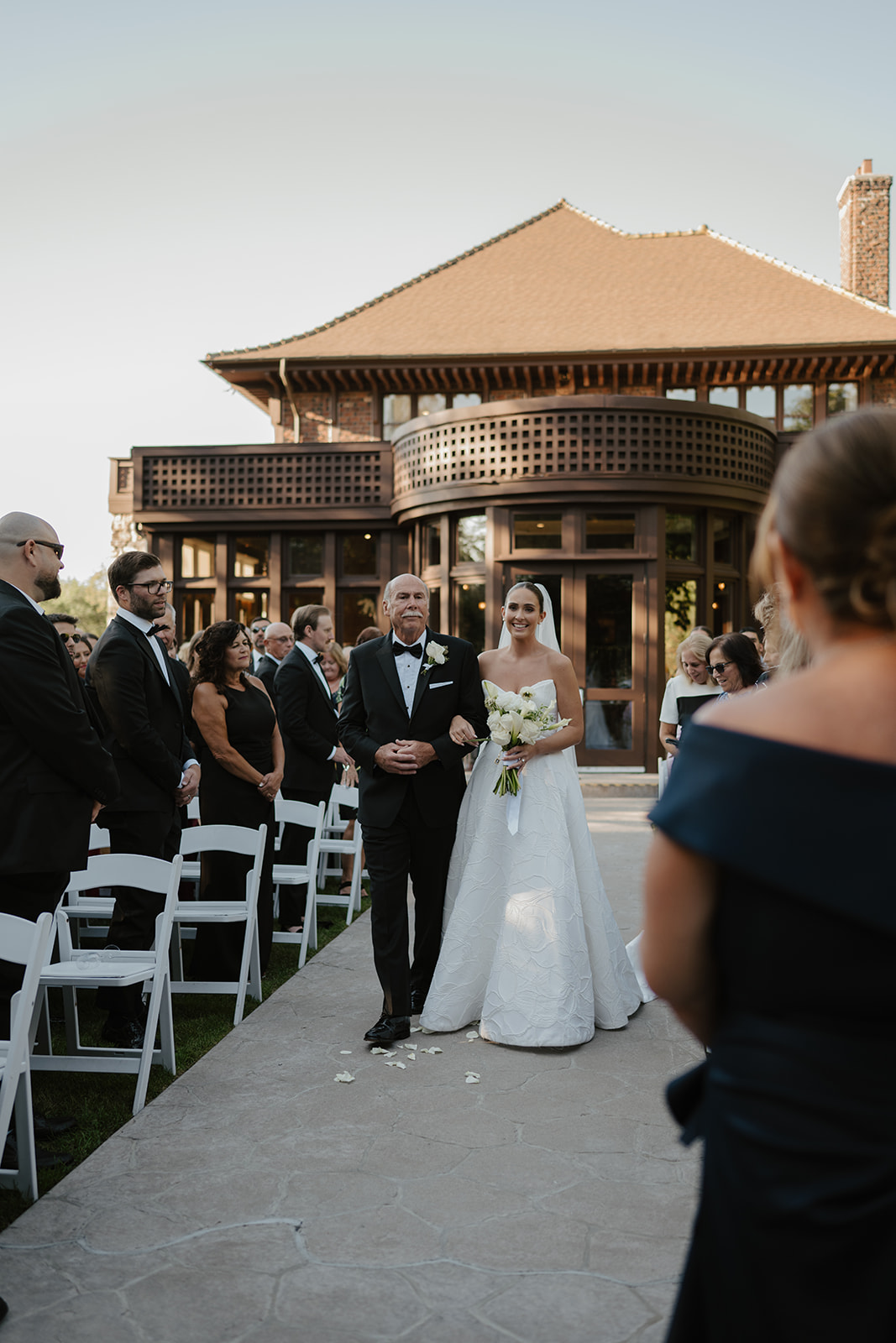 Smiling bride walking down the aisle arm-in-arm with her father during the outdoor ceremony.